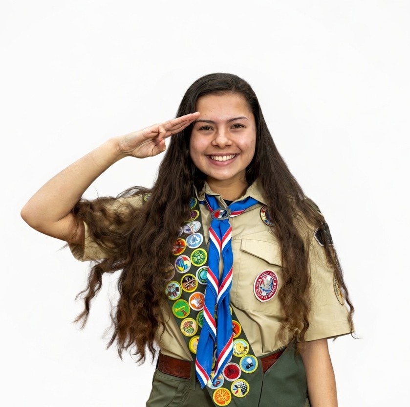 Joven scout realizando el saludo scout con orgullo